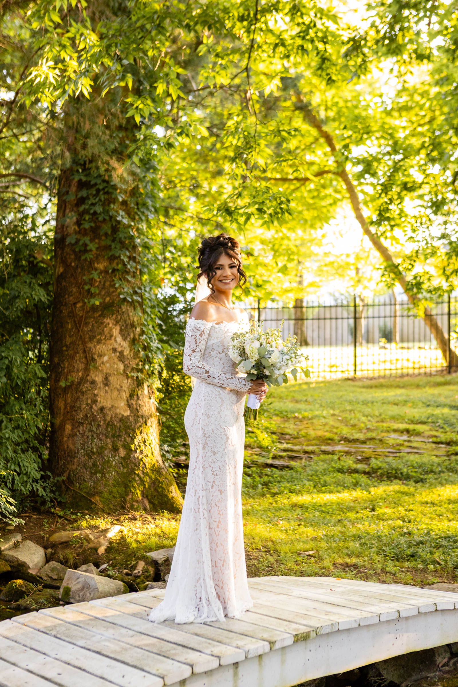 Bride standing on garden bridge in golden light