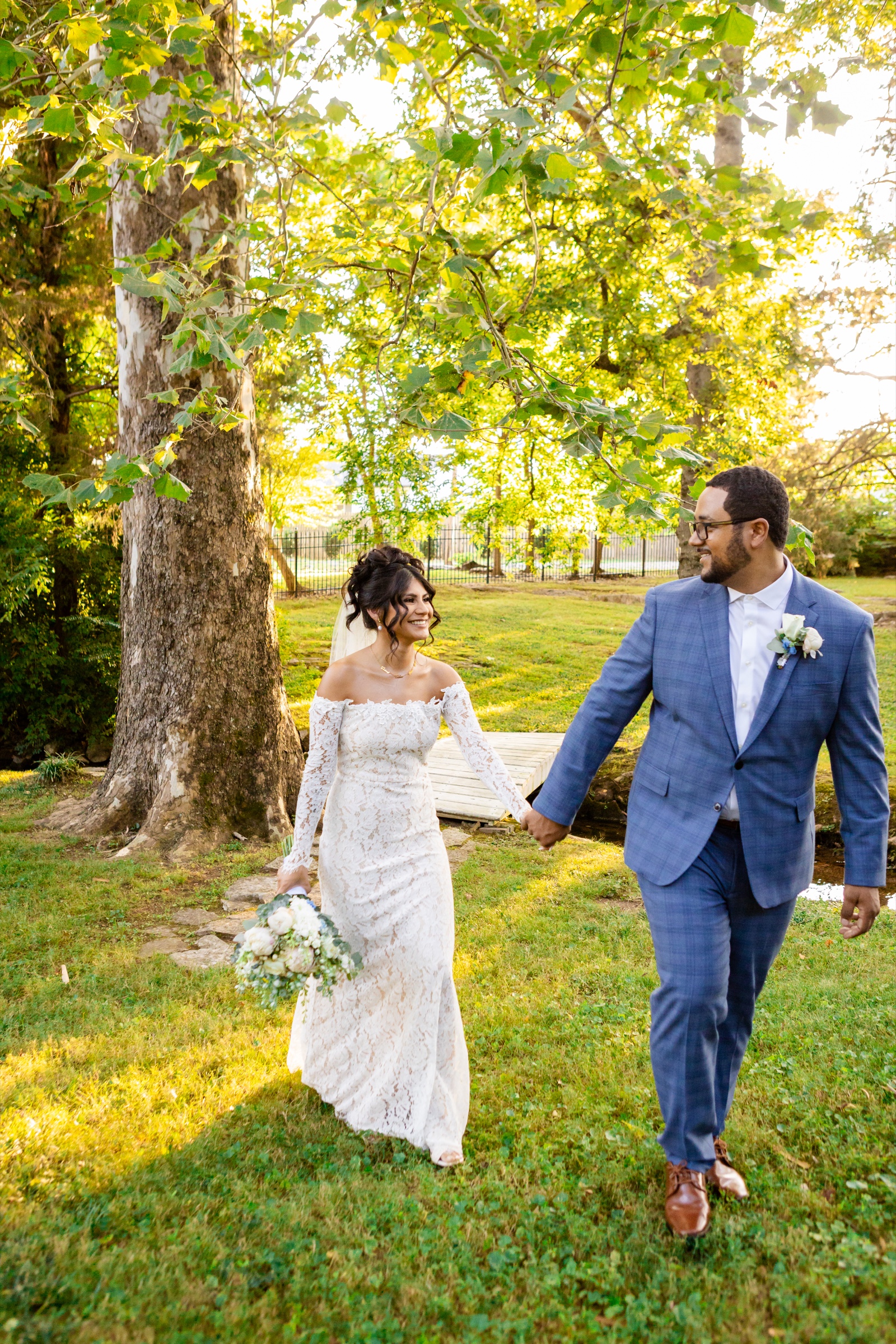 Couple walking together at golden hour under trees