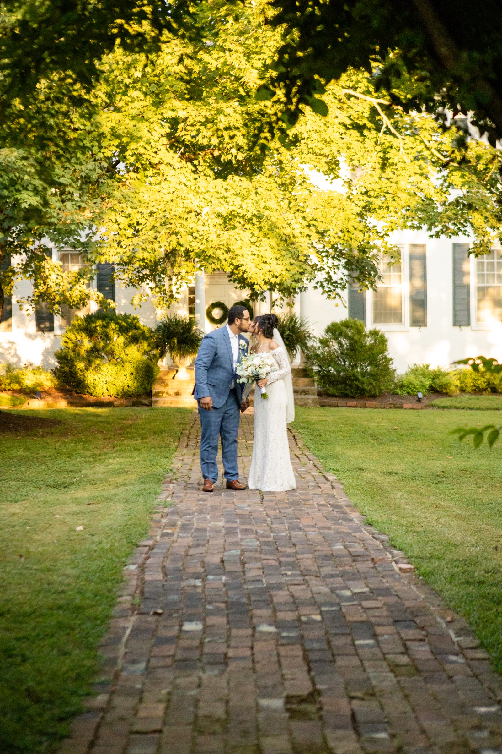 Marilyn and Darryus kiss on the brick path at Spring Haven Mansion