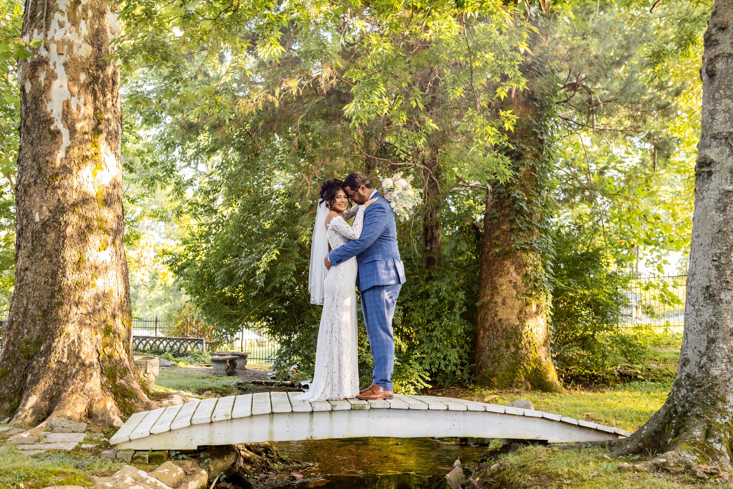Couple kissing on garden bridge surrounded by trees