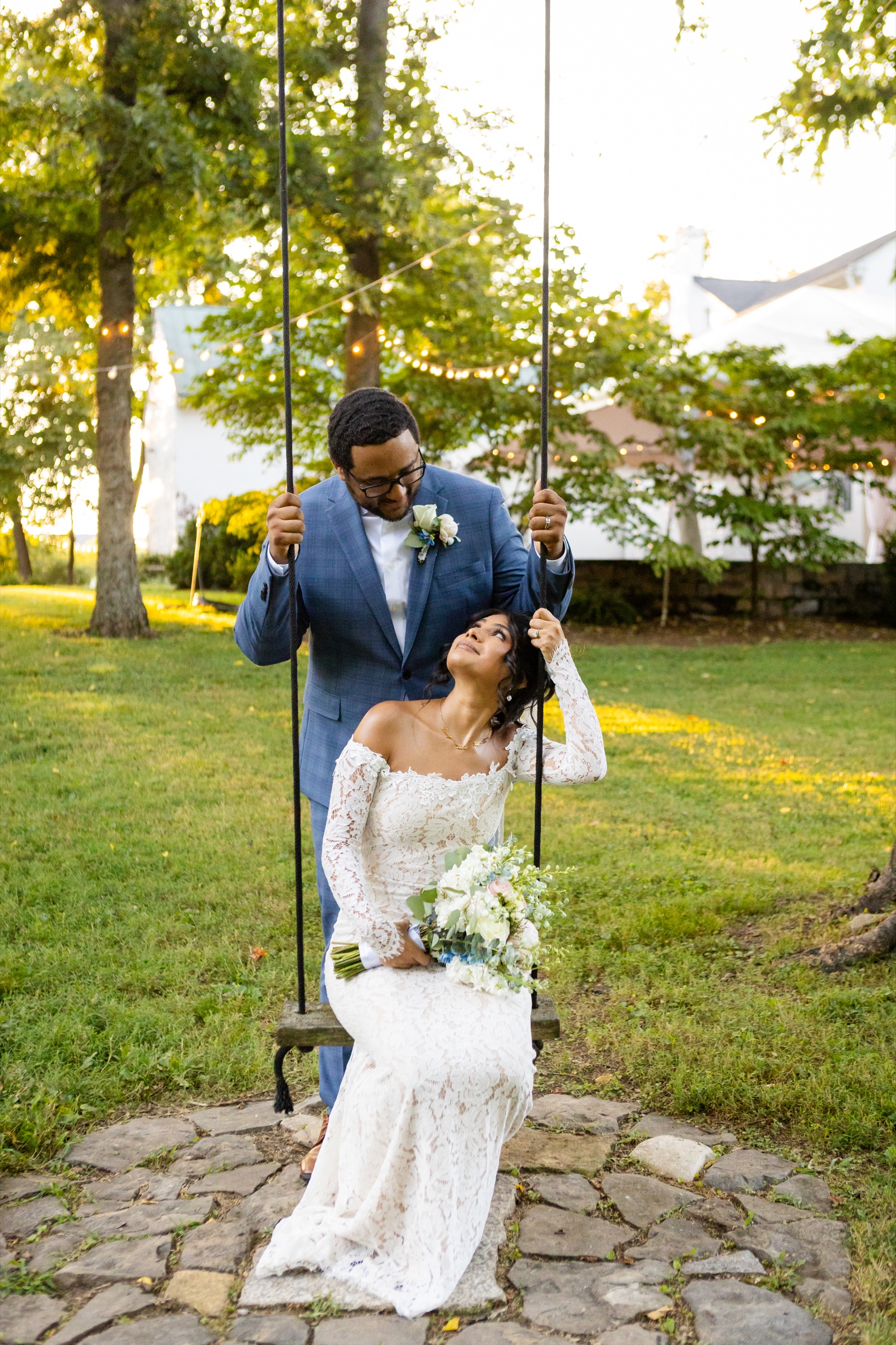 Bride looking up at groom on tree swing at sunset